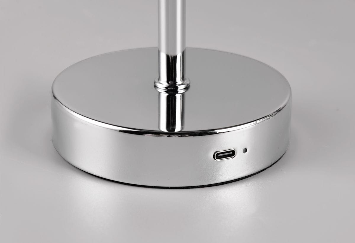 Lampa stołowa Jeff z chromowanym podstawą, widok na okrągłą podstawę z wbudowanym portem USB-C. Gładka, lustrzana powierzchnia refleksyjna, elegancki design. Produkt w pozycji stojącej, na szarym tle.