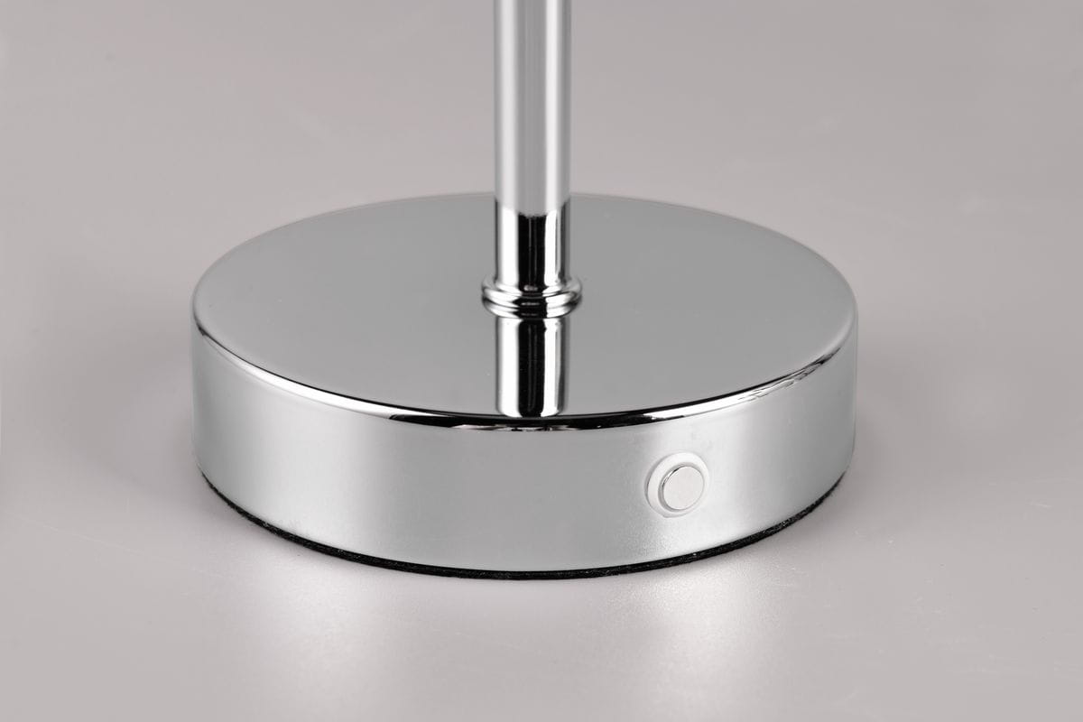 Lampa stołowa Jeff z chromowanym podstawą, z widocznym przyciskiem włączania. Elegancka, okrągła podstawa z gładkim wykończeniem, podtrzymująca smukły słupek. Idealna do nowoczesnych wnętrz, na białym tle.