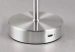 Lampa stołowa Jeff w kolorze niklowym z podstawą o okrągłym kształcie. Widoczny port USB-C do ładowania. Powierzchnia matowa, elegancka, z delikatnym połyskiem. Ujęcie z boku, ukazujące detale podstawy i teksturę materiału.