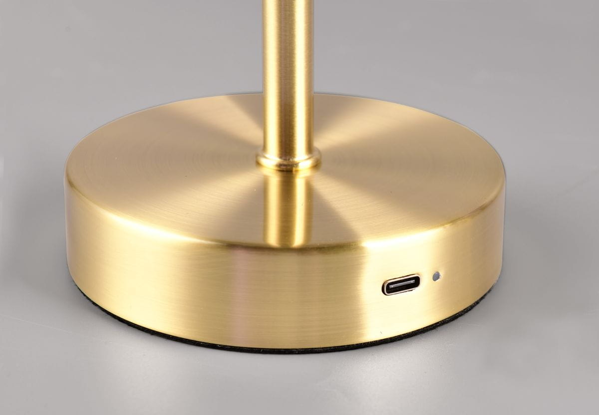 Lampa stołowa Jeff z mosiądzu matowego, z okrągłą podstawą. Widoczny port USB-C oraz mała dioda sygnalizacyjna. Kąt ujęcia zbliżony na detal podstawy.