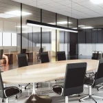 Lampa wisząca Sigi IV w kolorze czarnym, z jedną diodą LED o mocy 36W i temperaturze barwowej 3000K. Ujęcie z boku, zawieszona nad owalnym stołem w nowoczesnym biurze, w tle widać szklane ściany i krzesła.