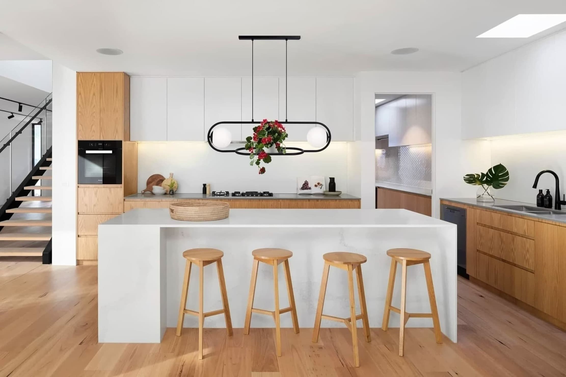 Lampa wisząca Finestra 2-punktowa w kolorze czarnym, z dwoma kulistymi kloszami, umieszczona nad białym blatem kuchennym. Kąt ujęcia frontalny, lampa zawieszona na dwóch kablach, otoczona nowoczesnym wnętrzem kuchni z drewnianymi akcentami.