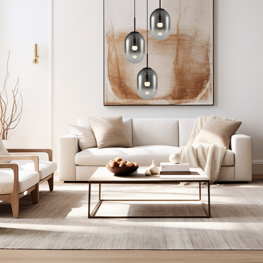 Lampa wisząca Alias 3xE14 w kolorze czarnym, z trzema szklanymi kloszami o owalnym kształcie, zawieszona nad jasną kanapą w nowoczesnym wnętrzu. Widoczne eleganckie detale i subtelne oświetlenie.