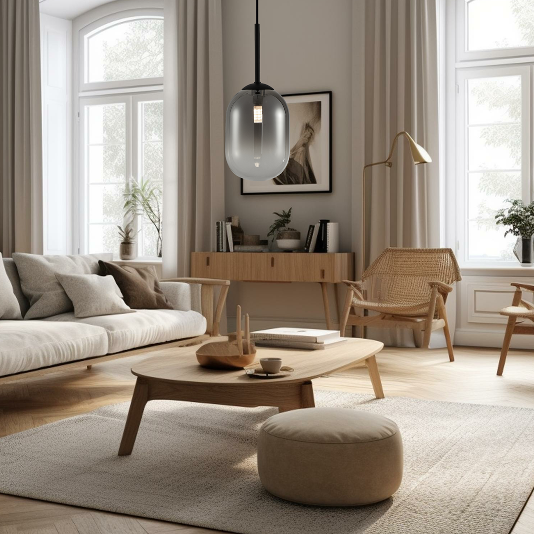 Lampa wisząca Alias D12 w kolorze czarnym, z przezroczystym kloszem w kształcie owalu, zawieszona na cienkim kablu. Widoczna w nowoczesnym wnętrzu z jasnymi zasłonami i drewnianymi meblami, tworzy elegancką atmosferę.