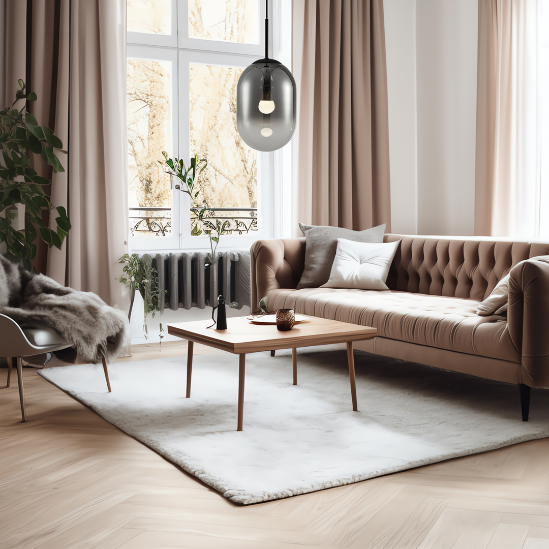 Czarna lampa wisząca Alias D24 z jedną oprawą E14, umieszczona nad drewnianym stolikiem w stylowym salonie. W tle widoczne okna z zasłonami oraz elegancka kanapa w odcieniu beżu.