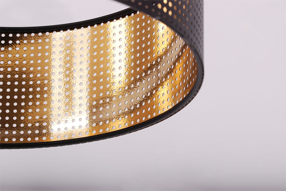 Kinkiet Zimbo K-5224 z oprawą w czarnym kolorze i wewnętrzną złotą powłoką, z perforacjami. Ujęcie zbliżeniowe na detal, pokazujące strukturę materiału oraz efekt świetlny. Idealny do nowoczesnych wnętrz.