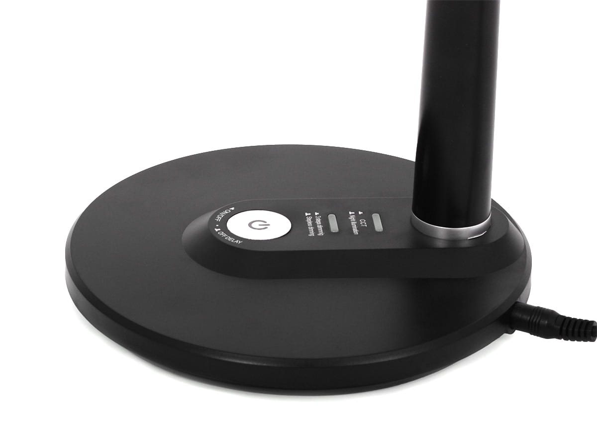 Czarna lampka biurkowa Dafi LED z jedną diodą LED o mocy 10W, z okrągłą podstawą i przyciskami sterującymi. Widoczny metalowy detal przy słupku lampy, z kablem zasilającym. Ujęcie pokazuje dolną część lampy z bliska.