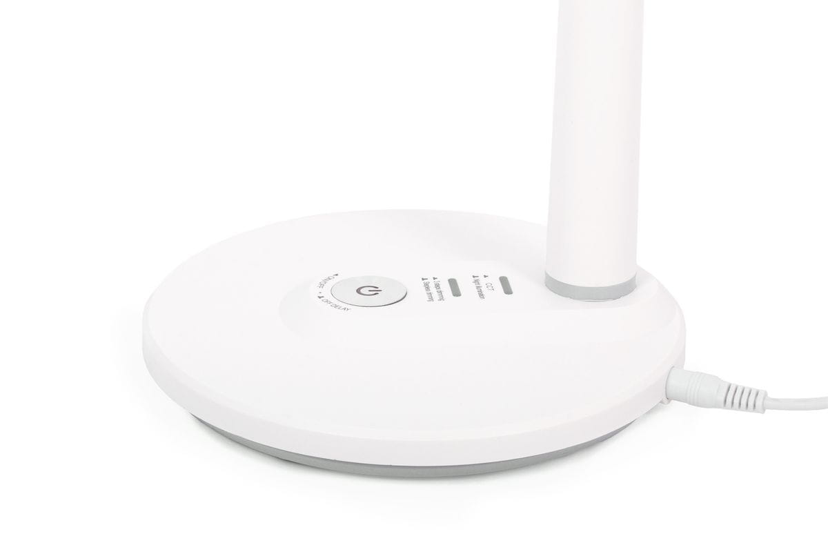 Biała lampka biurkowa Dafi z jedną diodą LED o mocy 10W. Posiada okrągłą podstawę z przyciskiem włączającym oraz regulacją jasności. Kąt ujęcia z boku, pokazujący szczegóły podstawy oraz kabel zasilający.