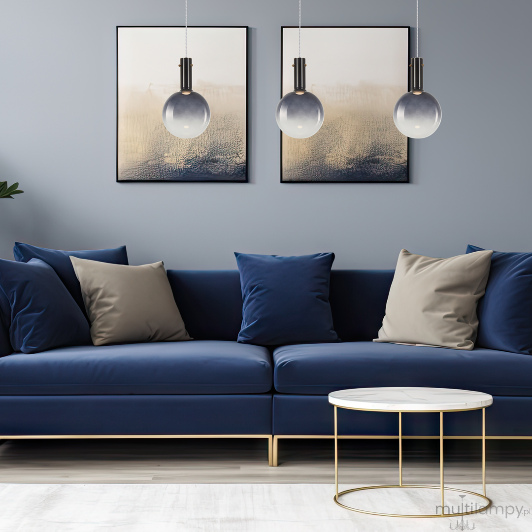 Czarna lampa wisząca Toronto z jedną oprawą GU10, zawieszona nad niebieską sofą z poduszkami, w otoczeniu dwóch obrazów na ścianie. Lampa ma minimalistyczny design z okrągłym kloszem i metalowym mocowaniem.