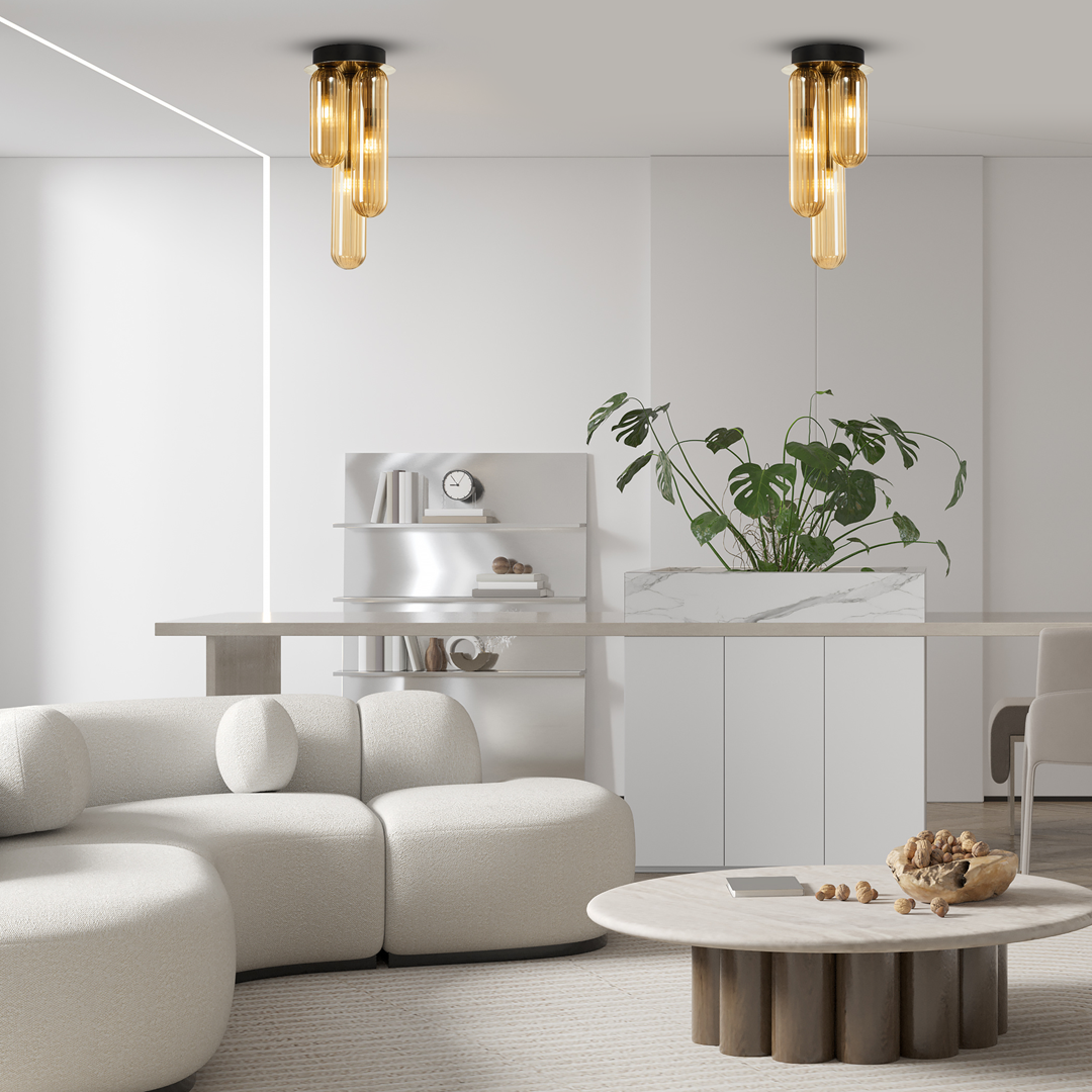 Lampa sufitowa Pax 3xG9 w kolorze złotym, z trzema szklanymi kloszami w kształcie cylindrów, zamontowana na czarnej podstawie. Widok z dołu, w nowoczesnym wnętrzu z jasnymi meblami i roślinami.