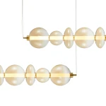 Lampa wisząca Daphne z jedną żarówką LED o mocy 40W. Złote elementy metalowe, szklane kule w odcieniu mlecznym, o różnych rozmiarach, zawieszone na cienkich linkach. Prosta, nowoczesna forma, idealna do eleganckich wnętrz.