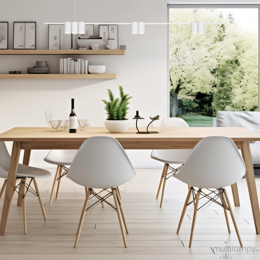 Lampa wisząca Genesis 7xGU10 w kolorze białym, zamontowana nad drewnianym stołem. Posiada minimalistyczny design z sześcioma punktami świetlnymi. W tle widoczna roślinność oraz nowoczesne meble w jasnym wnętrzu.