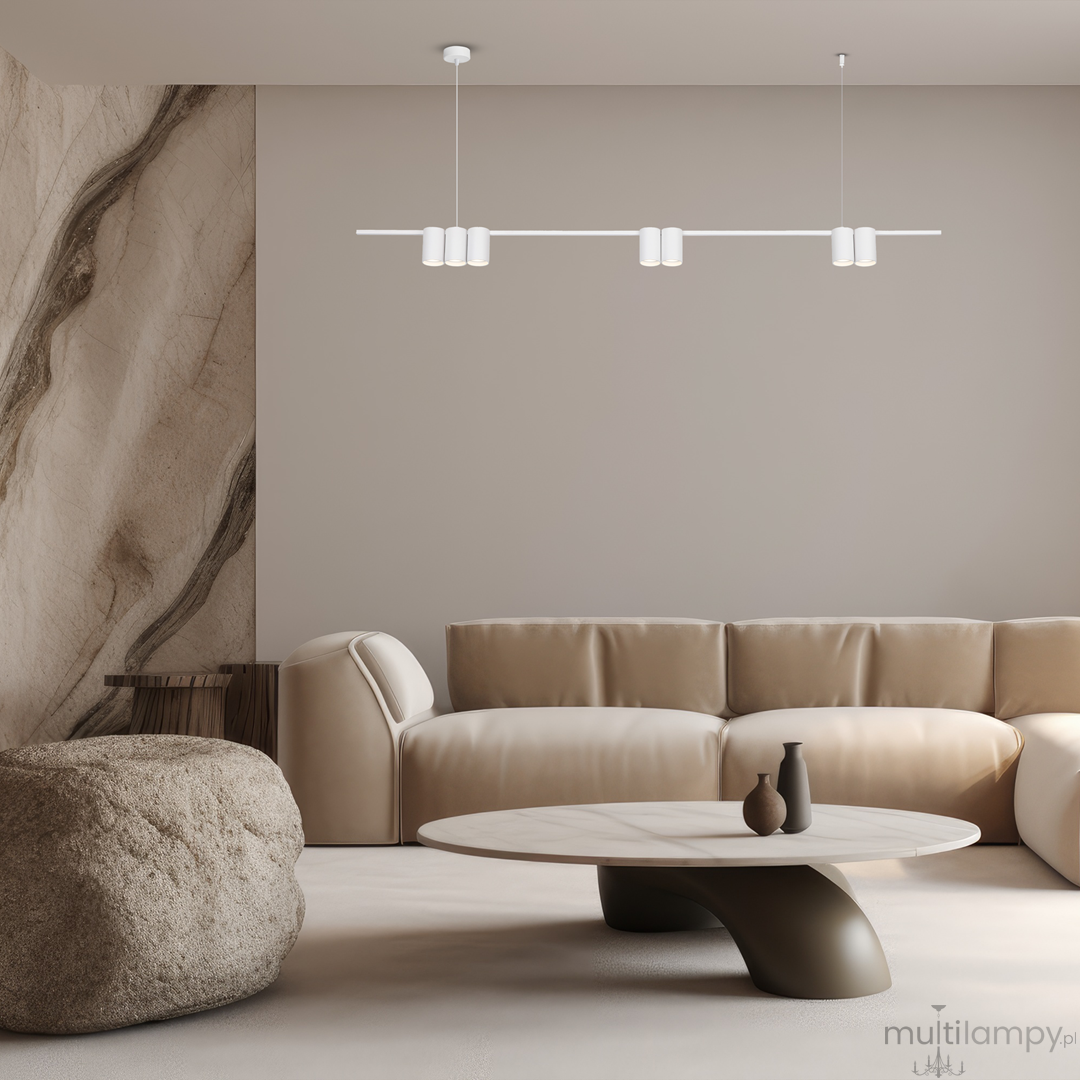 Lampa wisząca Genesis 7xGU10 w białym kolorze, zamontowana na suficie. Posiada prostą, minimalistyczną konstrukcję z sześcioma okrągłymi kloszami rozmieszczonymi na długim ramieniu. W tle widoczny jasny salon z kanapą i okrągłym stołem.
