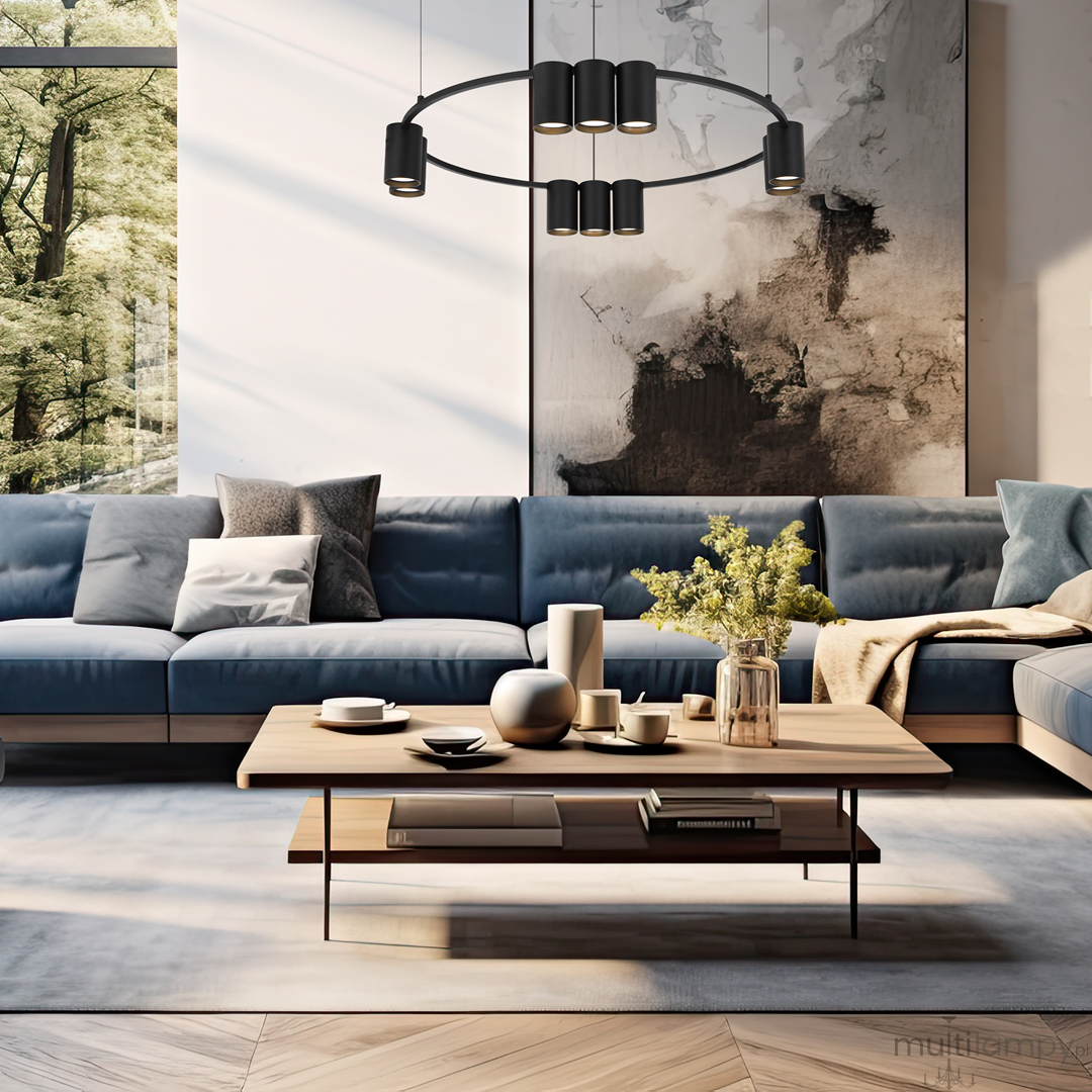 Czarna lampa wisząca Genesis z 10 gniazdami GU10, umieszczona nad drewnianym stołem w nowoczesnym salonie. Lampa ma minimalistyczny, okrągły kształt i jest zawieszona na cienkich linkach. W tle widoczna stylowa sofa oraz dekoracje.