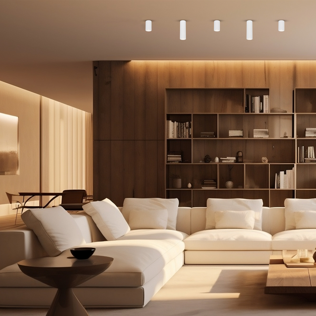 Biała lampa sufitowa Genesis H20 z jedną oprawą GU10, zamontowana na suficie w nowoczesnym wnętrzu. W tle widoczna drewniana ściana oraz jasna sofa z poduszkami. Oświetlenie stwarza przytulną atmosferę.