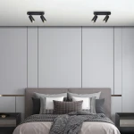 Lampa sufitowa Flower w kolorze czarnym i złotym z dwoma reflektorami GU10, zamontowana na suficie. Widok z góry, w nowoczesnym wnętrzu sypialni z szarymi ścianami i łóżkiem z poduszkami.