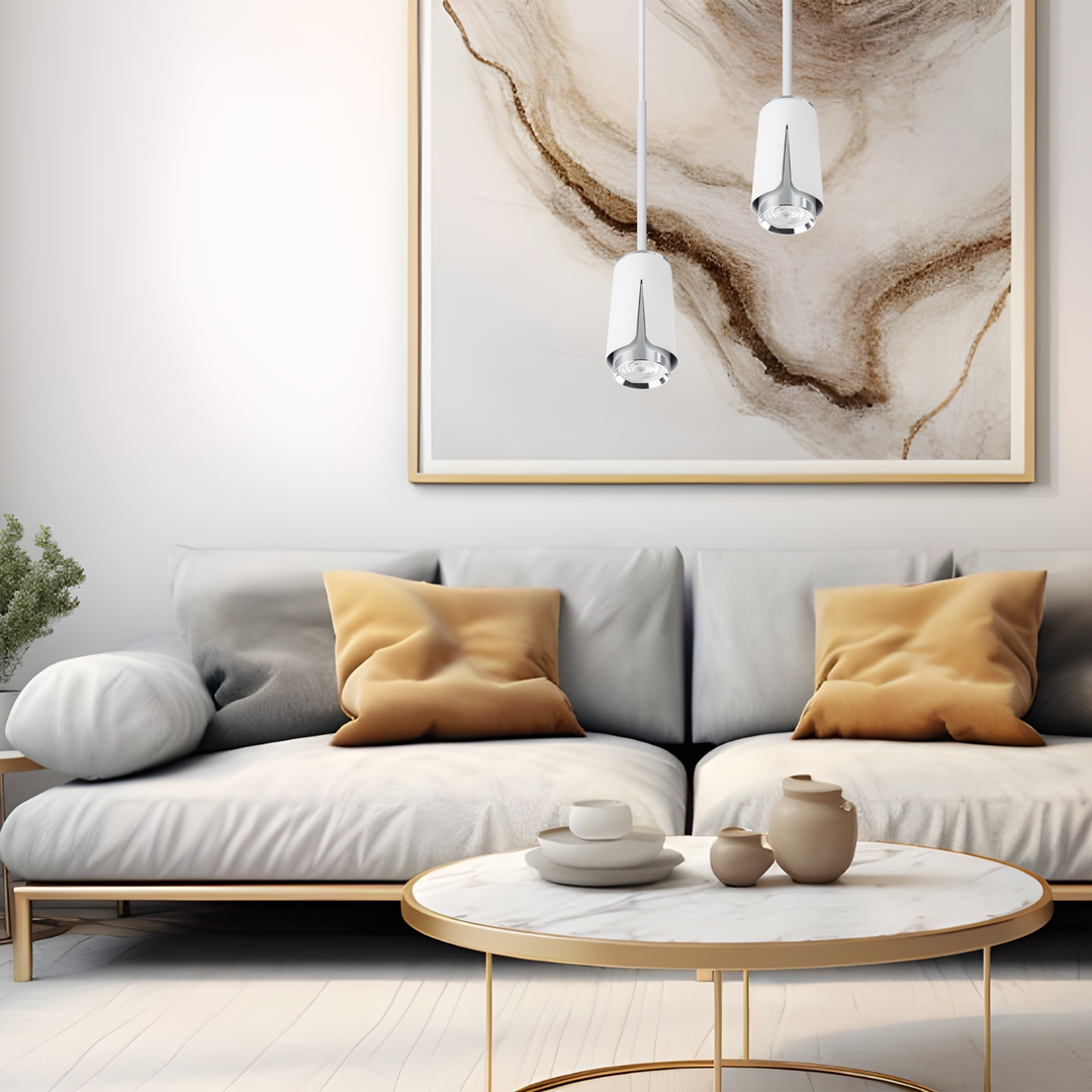 Lampa wisząca Flower 1xGU10 w białym kolorze z chromowanymi detalami, zawieszona w nowoczesnym wnętrzu nad okrągłym stołem. Tło stanowi jasna ściana z abstrakcyjnym obrazem, a na kanapie leżą poduszki w odcieniach szarości i beżu.
