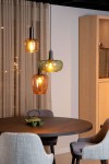 Lampa wisząca Ilona 3xE27 w kolorze czarnym z trzema szklanymi kloszami w odcieniach brązu i zieleni. Zawieszona na cienkim przewodzie w nowoczesnym wnętrzu, nad okrągłym stołem. Widoczne ciepłe światło żarówek.