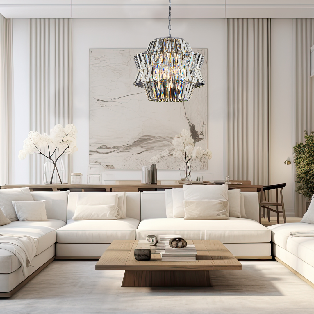 Lampa wisząca Crown w kolorze chromu z 12 miejscami na żarówki E14. Posiada elegancki, geometryczny design z kryształowymi detalami, zawieszona na metalowym łańcuchu. Umieszczona w nowoczesnym wnętrzu z białymi meblami i minimalistycznymi dekoracjami.