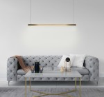 Lampa wisząca Linus 80 w kolorze złotym, z jedną żarówką LED 15W, zawieszona nad szarym, pikowanym sofą. W tle jasna ściana, a na stole znajduje się kilka książek i dekoracji.