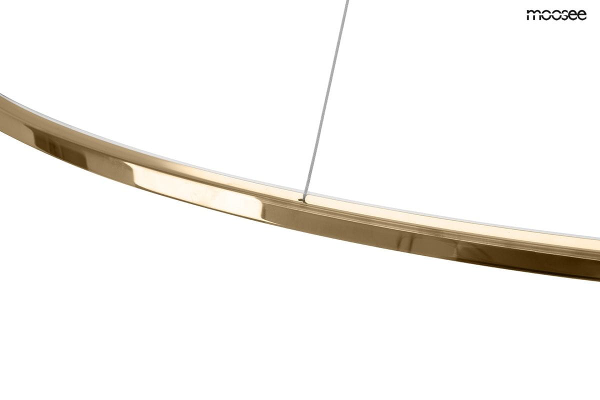Lampa wisząca Ring Slim 120 w kolorze złotym. Zbliżenie na metalowy pierścień z błyszczącą powierzchnią. Widać przezroczysty przewód mocujący. Produkt przeznaczony do montażu sufitowego, z możliwością zdalnego sterowania za pomocą pilota.