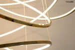 Lampa wisząca Ring Slim M w kolorze złotym, składająca się z kilku okrągłych, zakrzywionych elementów LED. Widok z góry, ukazujący delikatne linie świetlne i lśniący metaliczny materiał. Produkt zawiera pilot do zdalnego sterowania.