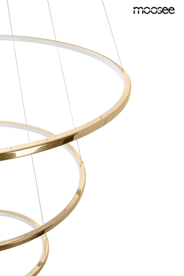 Lampa wisząca Ring Slim L w kolorze złotym z pięcioma źródłami LED. Produkt ma trzy okrągłe pierścienie, zawieszone na cienkich linkach. Widoczny jest także napis moosee w górnej części zdjęcia.