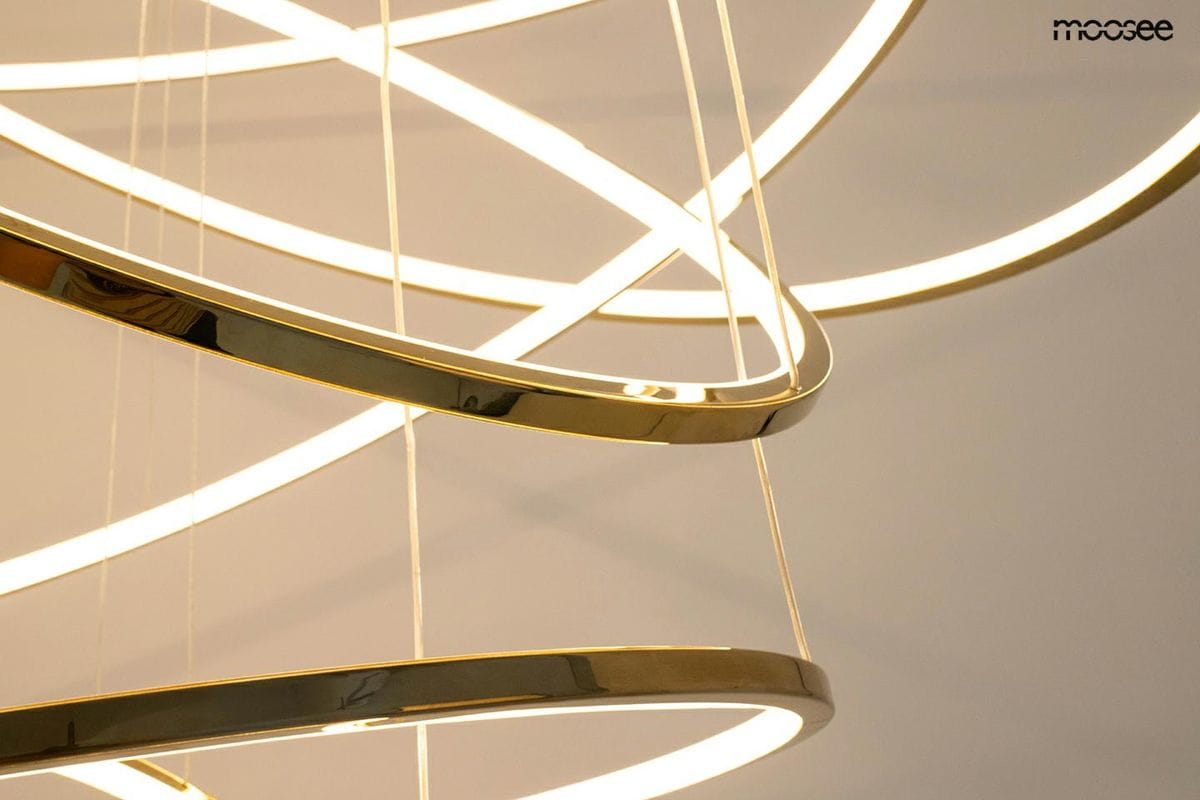 Złota lampa wisząca Ring Slim L z pilotem, z pięcioma diodami LED, w formie spiralnych obręczy. Ujęcie zbliżeniowe na detale konstrukcji, podkreślające błyszczący wykończenie. Tło jasne, minimalistyczne, co eksponuje elementy lampy.