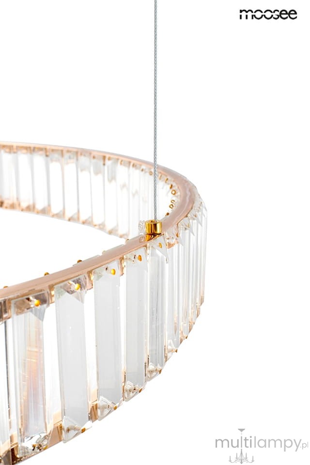 Złota lampa wisząca Liberty 3B z trzema źródłami LED, o okrągłej konstrukcji z przezroczystymi, prostokątnymi elementami. Widoczny detal zawieszenia na cienkim przewodzie oraz dekoracyjne wykończenie z kryształowymi akcentami.