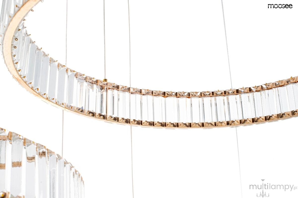 Lampa wisząca Liberty 3B z trzema źródłami LED, złota, z przezroczystymi, prostokątnymi kryształami ułożonymi w okrąg. Produkt zawieszony na cienkich linkach, ukazujący elegancki design oraz nowoczesne wykończenie.