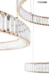 Lampa wisząca Liberty 3B w złotym kolorze, z trzema źródłami światła LED, posiada okrągłe pierścienie zdobione przezroczystymi kryształami. Widoczny detal to metalowe wykończenie i sznurki montażowe. Produkt wisi w powietrzu na białym tle.