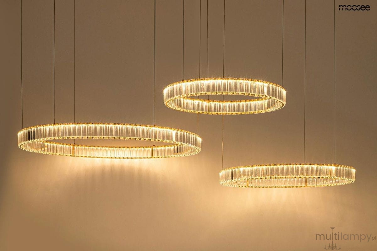 Lampa wisząca Liberty 3B z trzema okrągłymi kloszami LED w kolorze złotym. Klosze mają transparentne akcenty, zawieszone na cienkich linkach. Produkt o nowoczesnym designie, idealny do eleganckich wnętrz, na jednolitym tle.