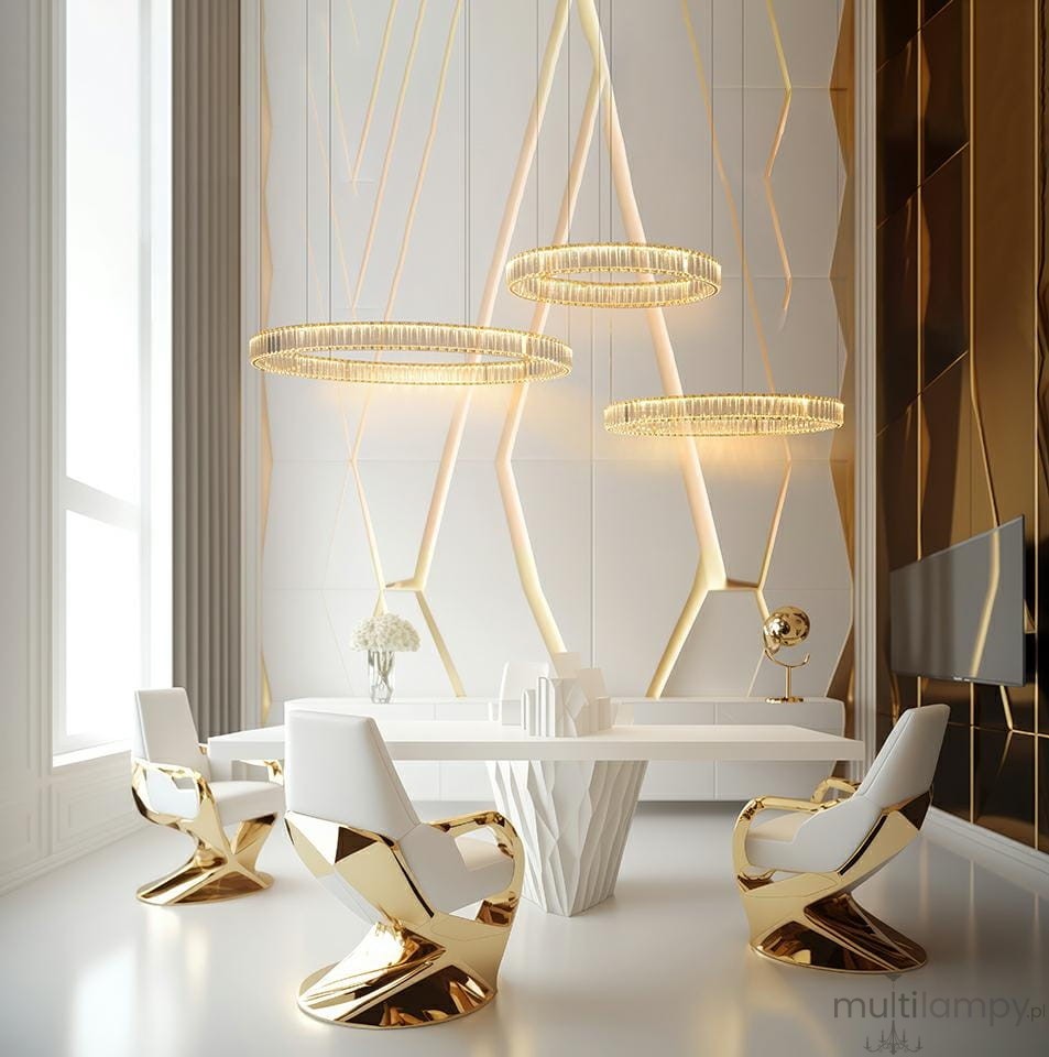 Lampa wisząca Liberty 3B w kolorze złotym, z trzema okrągłymi kloszami LED, zawieszona nad eleganckim stołem w nowoczesnym wnętrzu. Tło z geometrycznymi wzorami w odcieniach bieli i złota, z białymi krzesłami o złotych detalach.