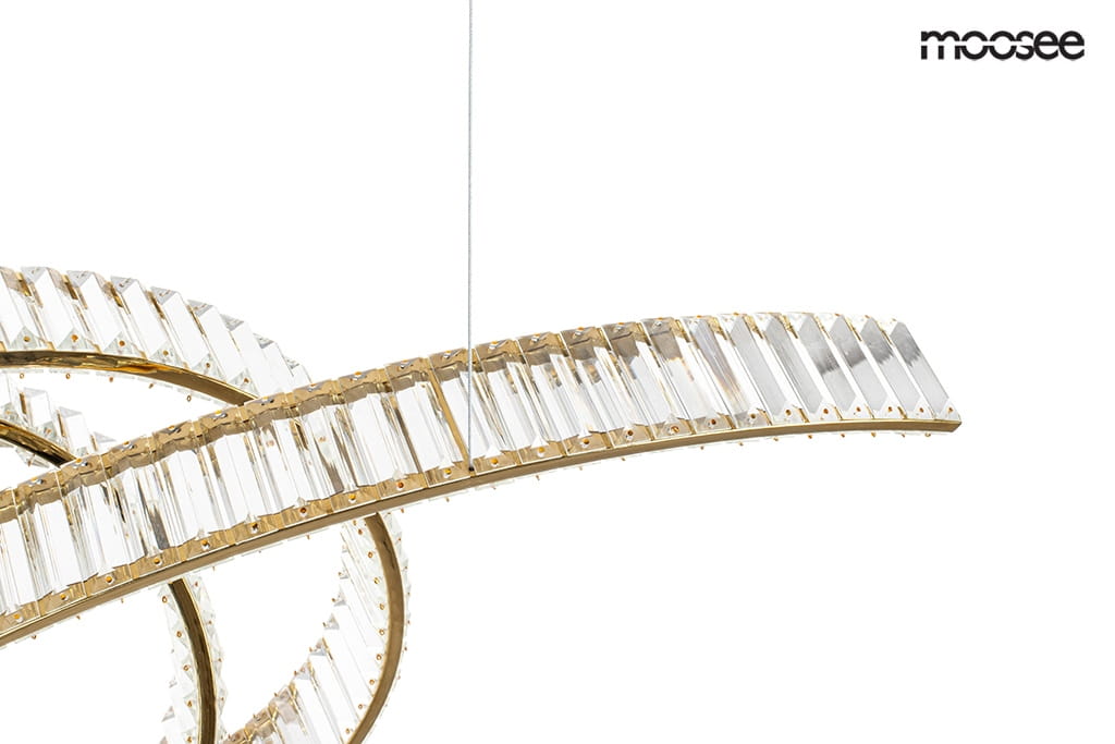Lampa wisząca Wave 120 w kolorze złotym, z przezroczystymi elementami, o nowoczesnym, falistym kształcie. Zawieszona na cienkim przewodzie, z widocznym źródłem światła LED 28W. Tło białe, co podkreśla elegancki design lampy.