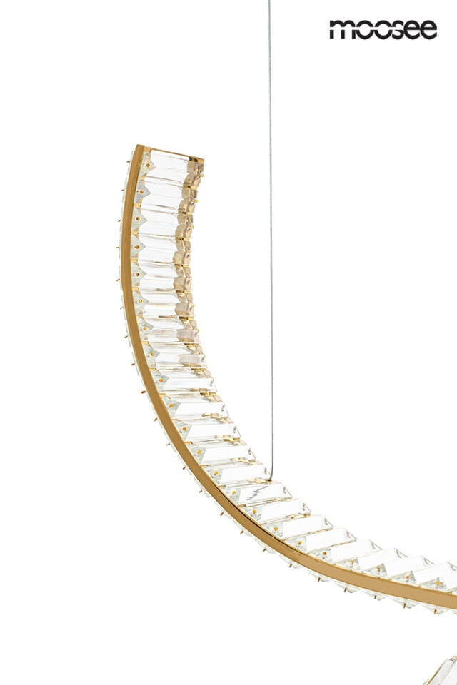 Lampa wisząca Wave 120 w kolorze złotym, z pojedynczym źródłem światła LED 28W. Ma półokrągły kształt z przezroczystymi elementami, zawieszona na cienkim przewodzie, z widocznymi detalami dekoracyjnymi. Tło jednolite, białe.