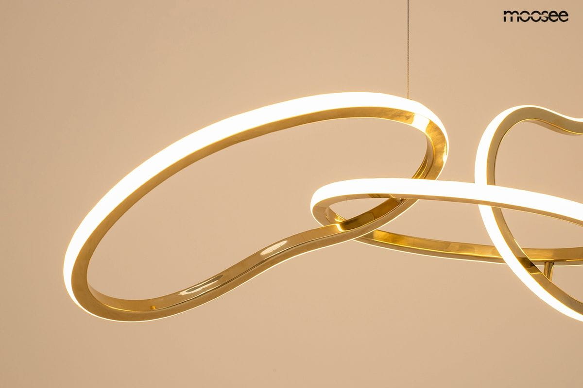 Lampa wisząca Jazz 5xLED/64W w kolorze złotym, składająca się z kilku owalnych, lekko zakrzywionych elementów. Widoczna jest delikatna, ciepła iluminacja LED. Ujęcie z bliska, podkreślające kształt i fakturę metalowych detali.