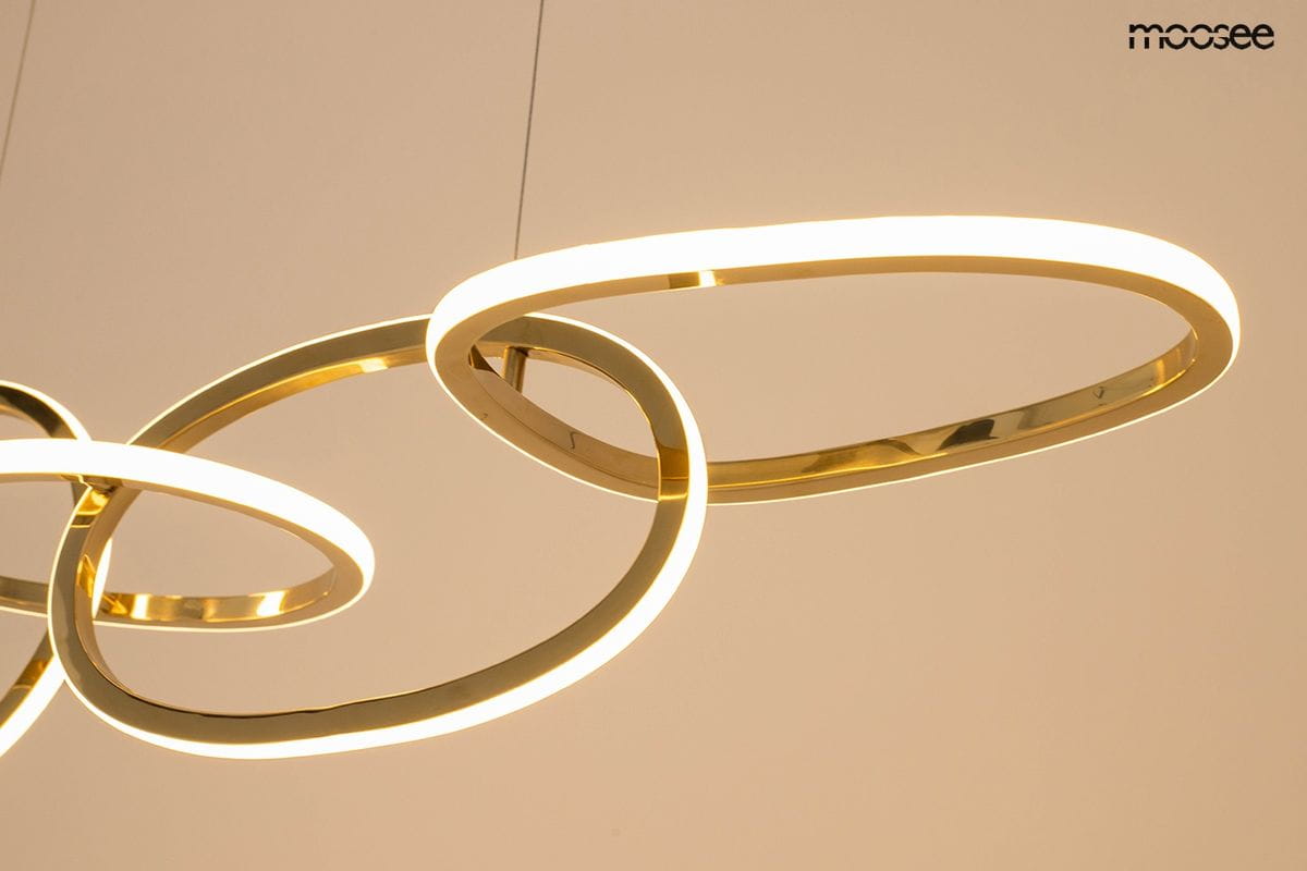 Lampa wisząca Jazz z pięcioma źródłami LED, o mocy 64W, w formie złotych, okrągłych pierścieni. Ujęcie z dołu, ukazujące subtelne podświetlenie krawędzi. Tło jasne, co podkreśla elegancki design lampy.