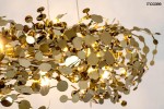 Lampa wisząca Monete 60 z 12 źródłami światła G4, w złotym kolorze. Ozdobna konstrukcja z metalowych, okrągłych elementów w różnych rozmiarach, tworząca efektowną aranżację. Zawieszona w górnej części, na jasnym tle.