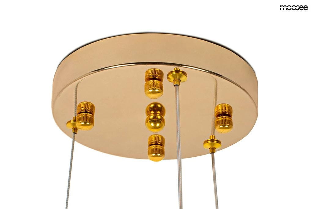 Lampa wisząca Monete 60 z 12 miejscami na żarówki G4, z metalowym, złotym kloszem. Ujęcie z dołu, pokazujące okrągłą podstawę i dekoracyjne elementy w złotym kolorze. Wisi na cienkich linkach, tworząc elegancki efekt świetlny.