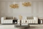 Lampa wisząca Monete 60 w kolorze złotym, z 12 źródłami światła G4, zawieszona w eleganckim wnętrzu. W tle widoczne jasne sofy i stół kawowy. Lampa ma organiczny kształt z dekoracyjnymi elementami przypominającymi liście.