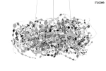 Lampa wisząca Monete 60 w kolorze chromu, składająca się z 12 źródeł światła G4. Ozdobna struktura z metalowych, okrągłych elementów w różnych rozmiarach, tworzy efektowną, dynamiczną formę. Zawieszona na cienkich linkach, na białym tle.