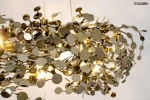 Lampa wisząca Monete 60 o chromowanej konstrukcji, z 12 lampkami G4. Posiada dekoracyjne elementy w formie okrągłych, metalicznych płyt w różnych rozmiarach, emitujących ciepłe światło, zawieszona na cienkich linkach.