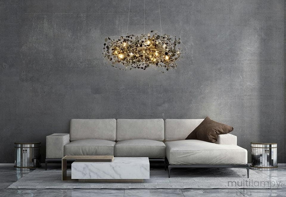 Lampa wisząca Monete 60 w kolorze chromu z 12 żarówkami G4, o organicznej formie z dekoracyjnymi elementami, zawieszona nad nowoczesną kanapą w odcieniach beżu. Tło w odcieniach szarości, minimalistyczne otoczenie.