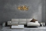Lampa wisząca Monete 60 w kolorze chromu z 12 żarówkami G4, o organicznej formie z dekoracyjnymi elementami, zawieszona nad nowoczesną kanapą w odcieniach beżu. Tło w odcieniach szarości, minimalistyczne otoczenie.
