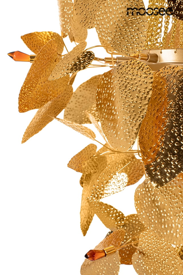 Lampa wisząca Paradiso z 4 gniazdami G9, w złotym kolorze. Ozdobiona metalowymi liśćmi o teksturowanej powierzchni. Widać również szklane elementy w kształcie kryształków, które dodają elegancji. Ujęcie z boku, zbliżenie na detale.