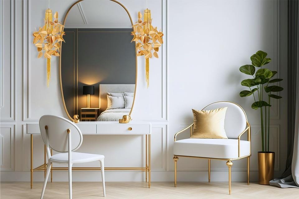 Lampa wisząca Paradiso 4xG9 w złotym kolorze, z eleganckimi dekoracjami, zawieszona nad toaletką w nowoczesnym wnętrzu. W tle lustro, biała toaletka, jasne krzesło i zielona roślina, podkreślające styl aranżacji.