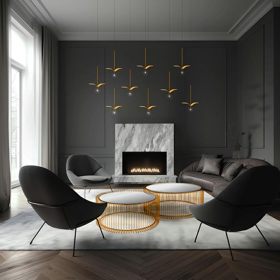 Lampa wisząca Gavi w kolorze złotym z 1 źródłem LED/5W, zawieszona w nowoczesnym wnętrzu z kominkiem. Widoczne są eleganckie, ciemne fotele oraz okrągłe stoliki kawowe z metalowym stelażem, na tle szarych ścian i dużych okien.