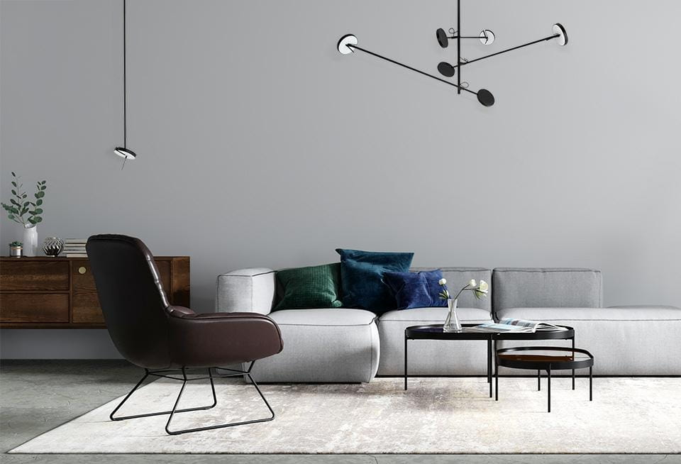 Lampa wisząca Bobbie w kolorze czarnym, z jedną żarówką LED 8W, zawieszona w nowoczesnym wnętrzu. Widoczna na tle szarej ściany, obok sofy i stolika kawowego, podkreśla styl aranżacji.