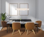 Lampa wisząca Casel w kolorze kawowym, z jednym źródłem LED o mocy 32W. Zawieszona nad stołem w jadalni, z nowoczesnym, prostym designem. W tle widoczna roślina i kanapa w odcieniach szarości.