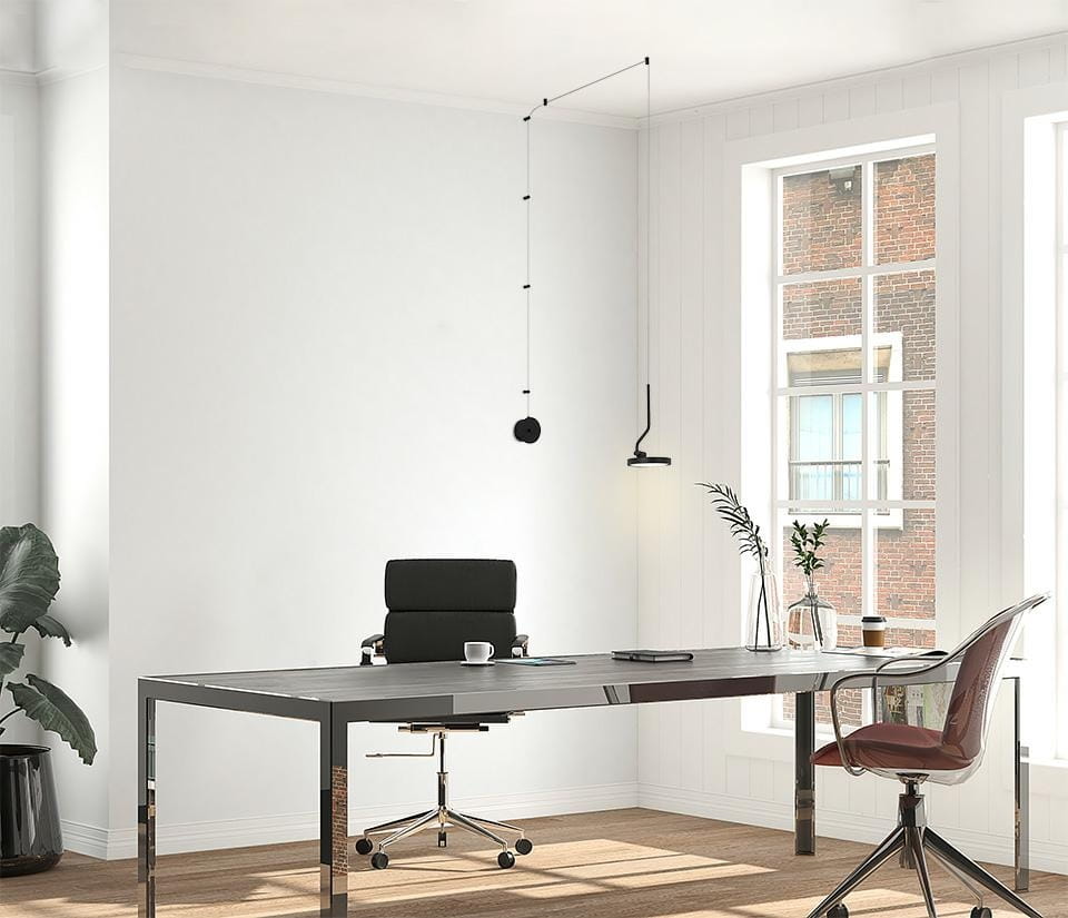 Czarna lampa wisząca Flat z 1xLED/10W, zawieszona w biurze, z minimalistycznym designem. Widoczna okrągła podsufitka oraz smukły przewód. W tle biurko z metalową podstawą i czarnym fotelem, na stole filiżanka i rośliny w wazonie. Jasne tło z oknami.